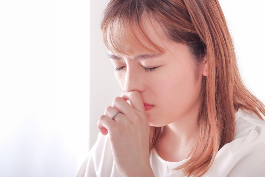鼻をふさぐ女性